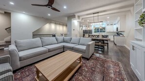 Amplia sala de estar con un sofá modular, una mesa de centro de madera y una alfombra estampada.