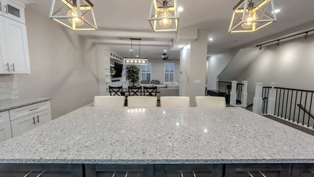 Una cocina moderna con una isla grande, luces colgantes y una escalera.