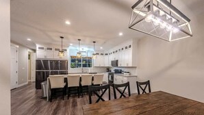 Una cocina moderna con armarios blancos, una isla central e iluminación colgante.