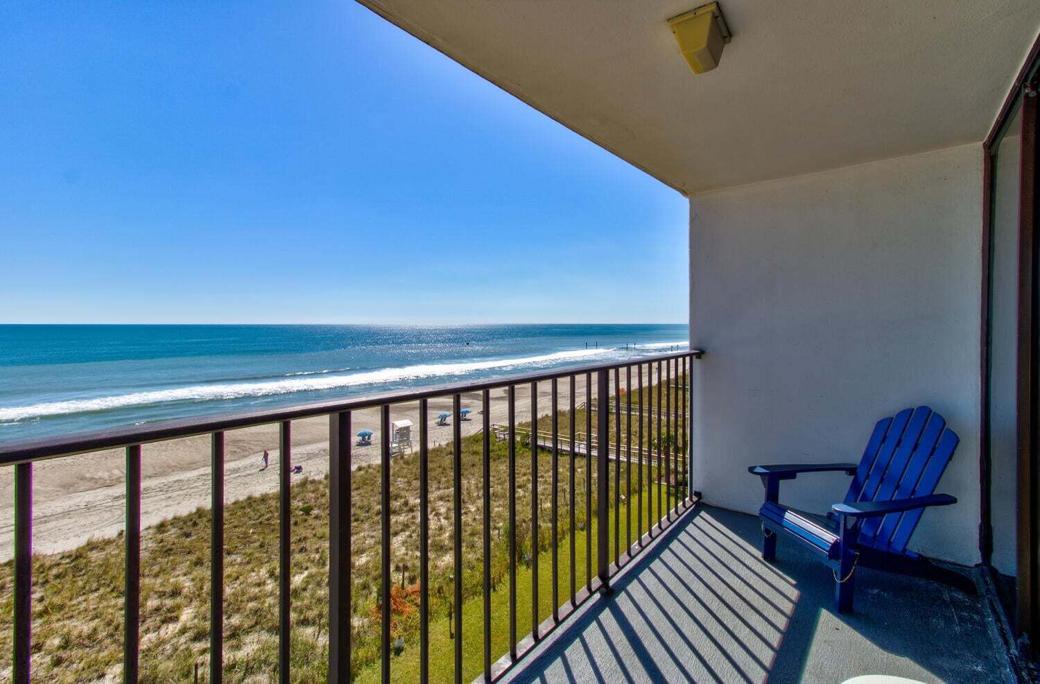 A balcony with a view of the beach and ocean.