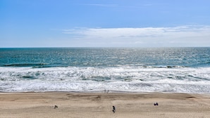 A beach with waves, a clear sky, and a few people. - Oceanfront retreat in Carolina Beach 0910 (Carolina Beach)