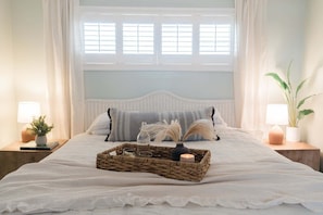 A neatly made bed with a woven tray, a lit candle, and decorative items. - Charming 2 Bedroom Oceanfront Condo in Carolina Beach with Stunning Views! (Carolina Beach)