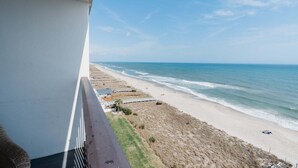 A balcony overlooking a beach with a clear view of the ocean and sandy shore. - Charming 2 Bedroom Oceanfront Condo in Carolina Beach 0912 (Carolina Beach)