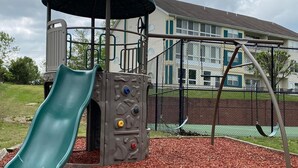 Ein Spielplatz mit Rutsche, Kletterbereich und Schaukeln.