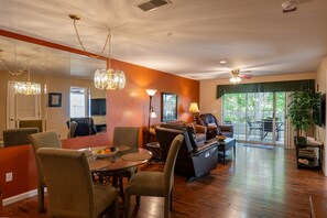 A modern living room with a dining area, hardwood floors, and a large window providing natural light. - Walk-In 2 Bedroom Condo | Easy Access + Golf Nearby | Quiet Branson Location (CH2-6) (Branson)