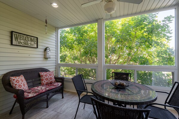A porch with a wicker sofa, a round table with chairs, and a 'WELCOME TO THE PORCH' sign. - Walk-In 2 Bedroom Condo | Easy Access + Golf Nearby | Quiet Branson Location (CH2-6) (Branson)