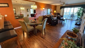 Ein modernes Wohnzimmer mit einem Glastisch, bequemen Sitzgelegenheiten, einer Couch und Blick ins Freie.