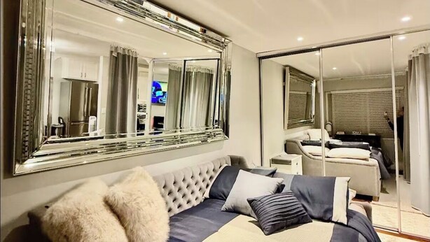 Ein modernes Schlafzimmer mit einem großen Bett, einem Spiegelkleiderschrank und einer separaten Sitzecke.