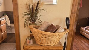 Een kamer met een houten kast, een rieten mand met handdoeken, een stofzuiger en een plant in een pot.