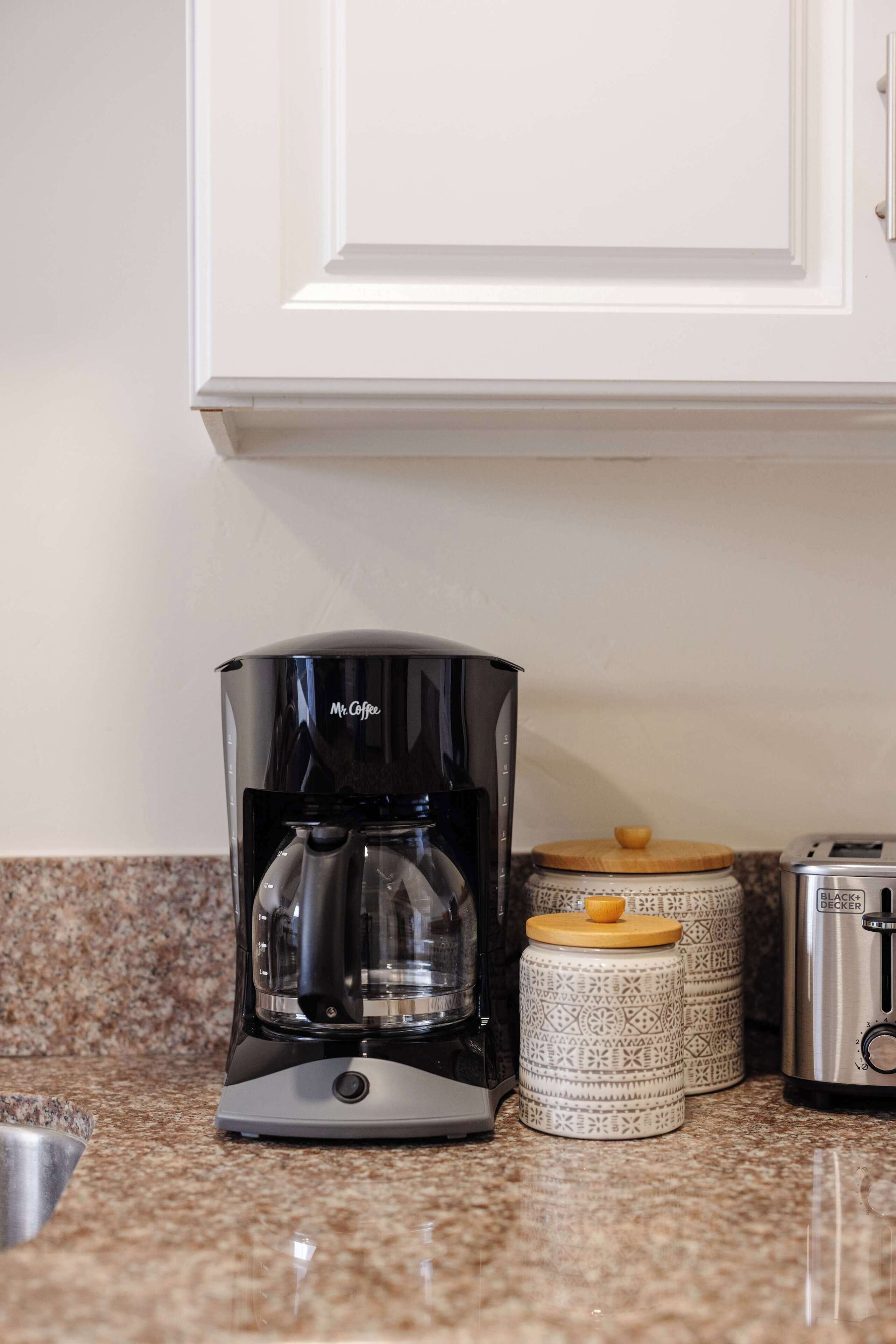 A kitchen with a coffee maker, two patterned containers, and a toaster.