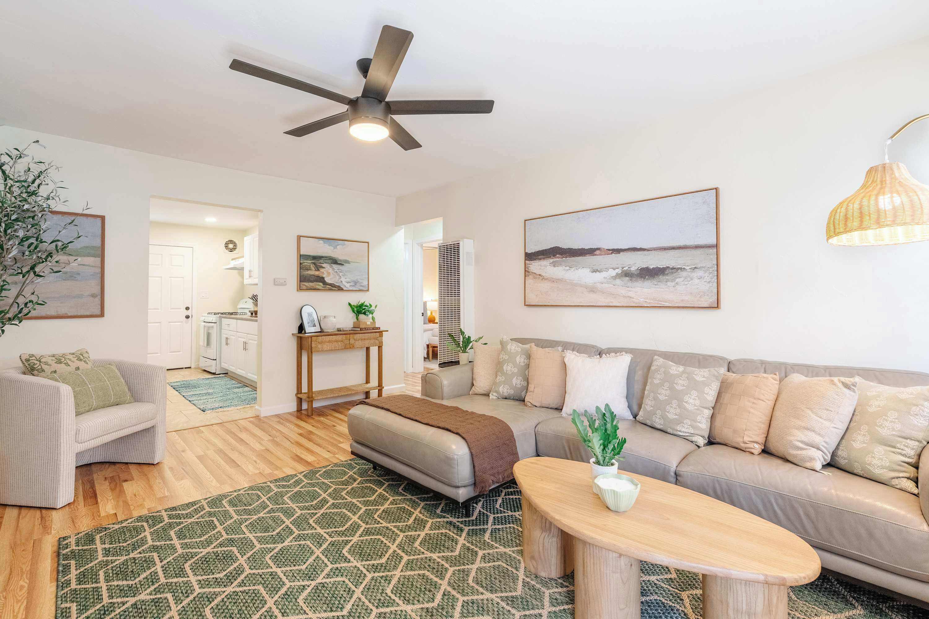 A modern living room with a sofa, ottoman, coffee table, and a ceiling fan.