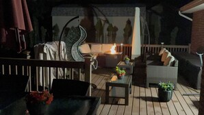 Patio esterno con focolare, posti a sedere e piante in vaso.