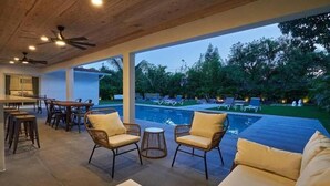 Ein überdachter Außenbereich mit Pool, Liegestühlen und Essbereich.