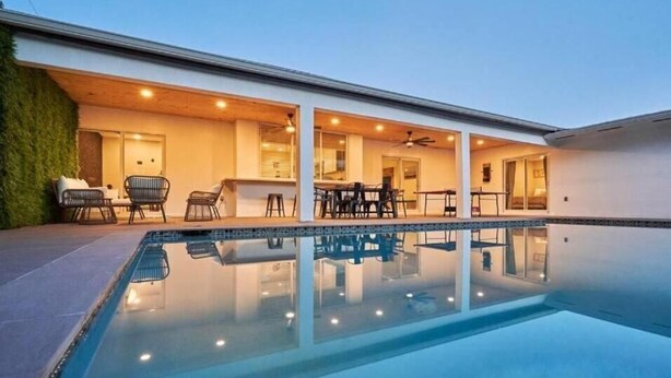Ein Pool mit Liegestühlen und Tischen, eine überdachte Terrasse sowie modernes architektonisches Design.