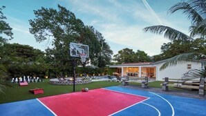 Ein Basketballplatz mit Korb, ein kleiner Pool und ein Gebäude mit einer Veranda.