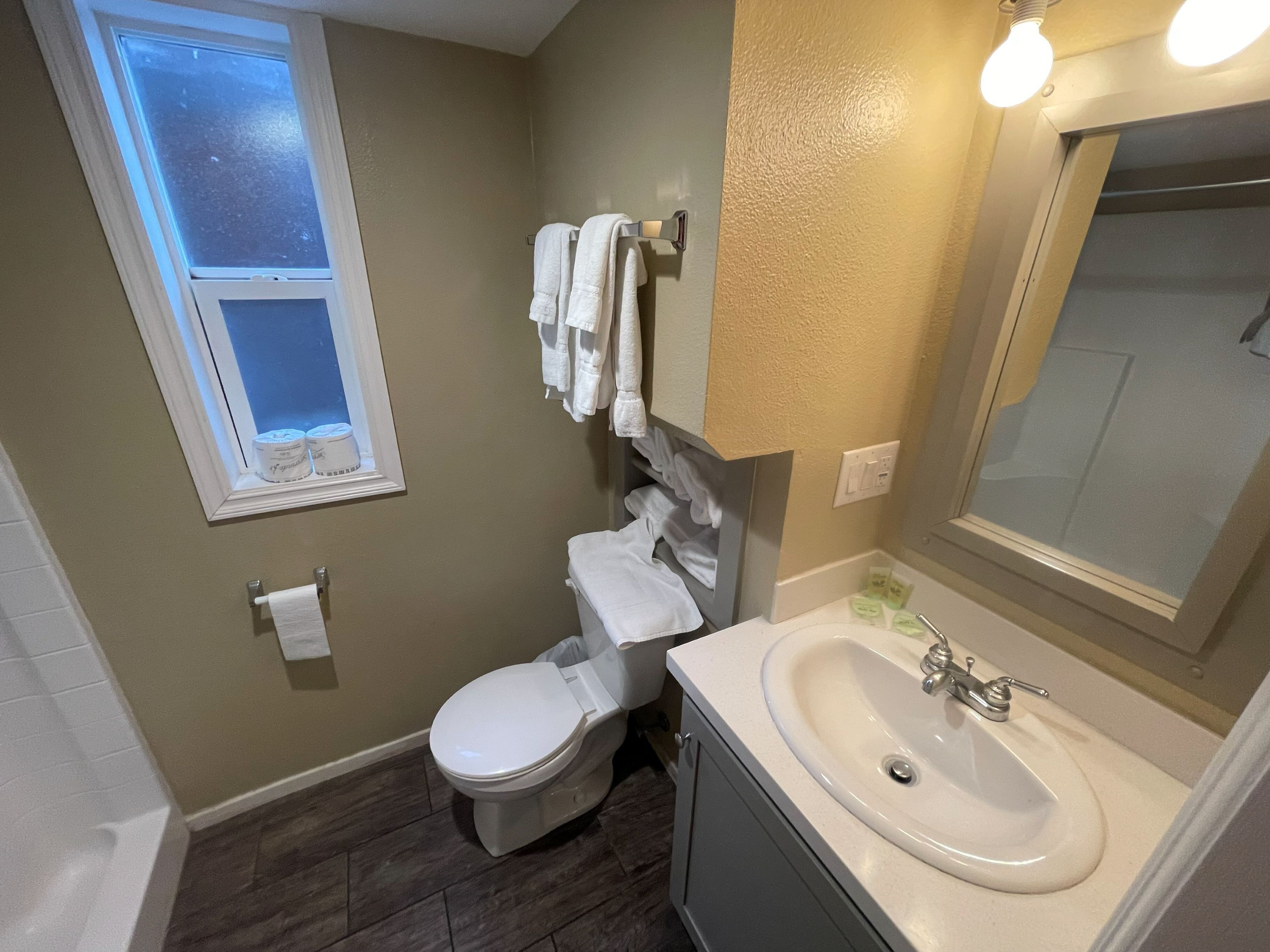 Een badkamer met toilet, wastafel en een raam.