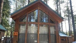 A wooden cabin with a large window, surrounded by snow and tall trees. - Wooded Cabin Perfect for South Lake Tahoe Day Trips (El Dorado County)