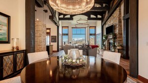 A dining area with a round table, chairs, a chandelier, and a stone fireplace. - Spacious 4BR home in Midway River Meadows (LT), perfect for adventures in Park City. (Midway)