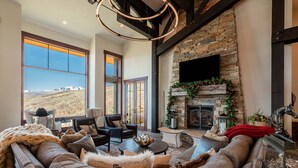 A spacious living room with a stone fireplace, large windows, and a cozy seating area. - Spacious 4BR home in Midway River Meadows (LT), perfect for adventures in Park City. (Midway)