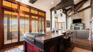 A kitchen with a large island, wooden beams, a stone fireplace, and a view of the mountains. - Spacious 4BR home in Midway River Meadows (LT), perfect for adventures in Park City. (Midway)
