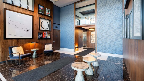 Un lobby moderno con mostrador de recepción de madera, zona de estar y obras de arte en las paredes.