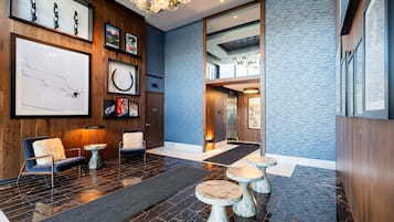 Un vestíbul modern amb taulell de recepció de fusta, zona de seients i obra d'art a les parets.