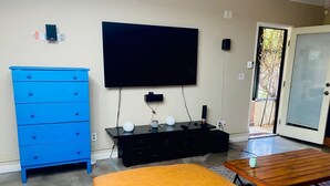 Ein Wohnzimmer mit einem blauen Kommoden, einer schwarzen Unterhaltungseinheit, einem großen Flachbildfernseher und einem Holztisch.