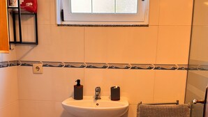 A bathroom with a sink, toilet, bidet, and a window.