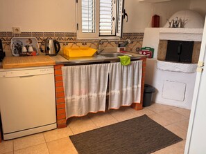 Una cocina equipada con lavavajillas, tabla de cortar, pileta y estufa.