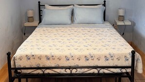 A bedroom with a bed, two bedside tables, a wall-mounted light fixture, and a decorative wall piece.