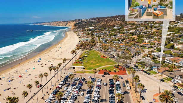 Un pueblo costero con playa, coches aparcados y zona residencial.