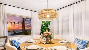 Una mesa redonda de comedor con platos blancos, cubiertos y una decoración central.