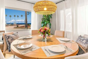 A round dining table with plates, cutlery, and a vase of flowers. - La Jolla Shores! Beach Across Street+Walk Everywhere (San Diego)