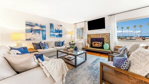 Una sala de estar con chimenea, un sofá, una mesa de centro y vista a la playa.
