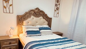 A bedroom with a bed, nightstands, a lamp, and decorative wall art.