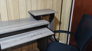 A workspace with a desk and chair, against a wooden wall.
