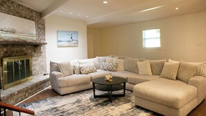 Ein Wohnzimmer mit Ecksofa, Couchtisch, Kamin und einem großen Gemälde an der Wand.