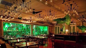 Ein Restaurant mit mehreren Speisetischen, hängenden Lampen und einem großen Aquarium.
