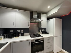 Una cocina moderna con electrodomésticos de acero inoxidable, estufa a gas, horno empotrado y refrigerador.