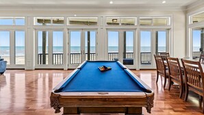 A pool table in a room with large windows overlooking the beach. - Beachfront 5BR | Hot Tub & Fire Pit | Game Room (Galveston)