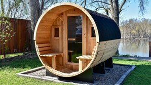 A wooden sauna structure with benches, a door, and a view of a lake.
