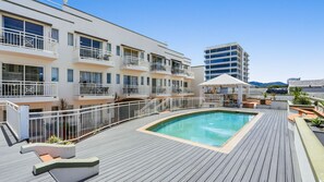 A rooftop pool area with a pool, outdoor seating, and a view of a modern building. - Stylish Executive Retreat in Cairns CBD | Pool, Parking & Walk to Esplanade (Cairns City)