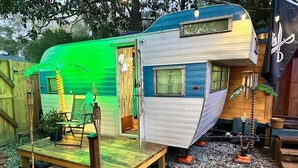 En campingvogn med veranda, lille træterrasse og et vindue.