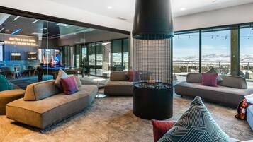 A modern living room with sofas, a fireplace, and large windows offering a view of a snowy landscape.