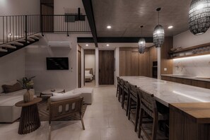 Una cocina moderna con encimera de mármol, sillas de madera e iluminación colgante.