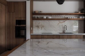 Una cocina moderna con armarios de madera, salpicadero de mármol y horno empotrado.