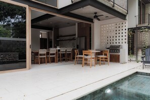Ein Essbereich im Freien mit Pool, Grill und Blick auf die Stadt.