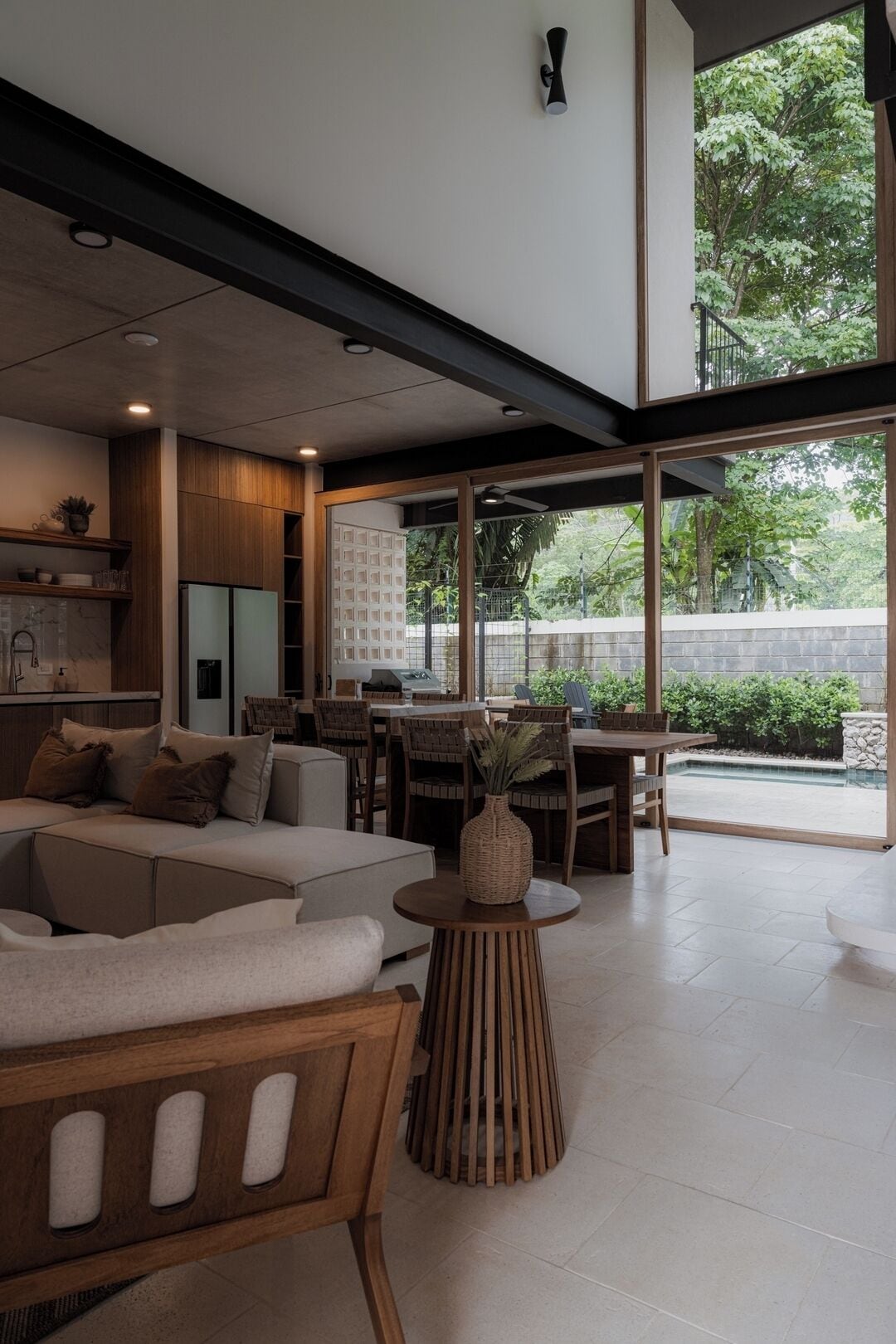 A modern interior with a sofa, dining table, and a view of greenery outside.