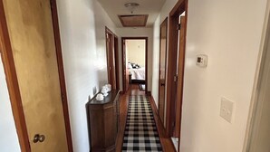 A hallway with wooden doors, a checkered carpet, and a ceiling vent. - Lakeside Retreat: Peaceful Jordan Lake Getaway (New Hill)