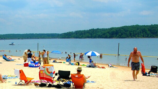 A beach with people, chairs, and umbrellas. - Lakeside Retreat: Peaceful Jordan Lake Getaway (New Hill)